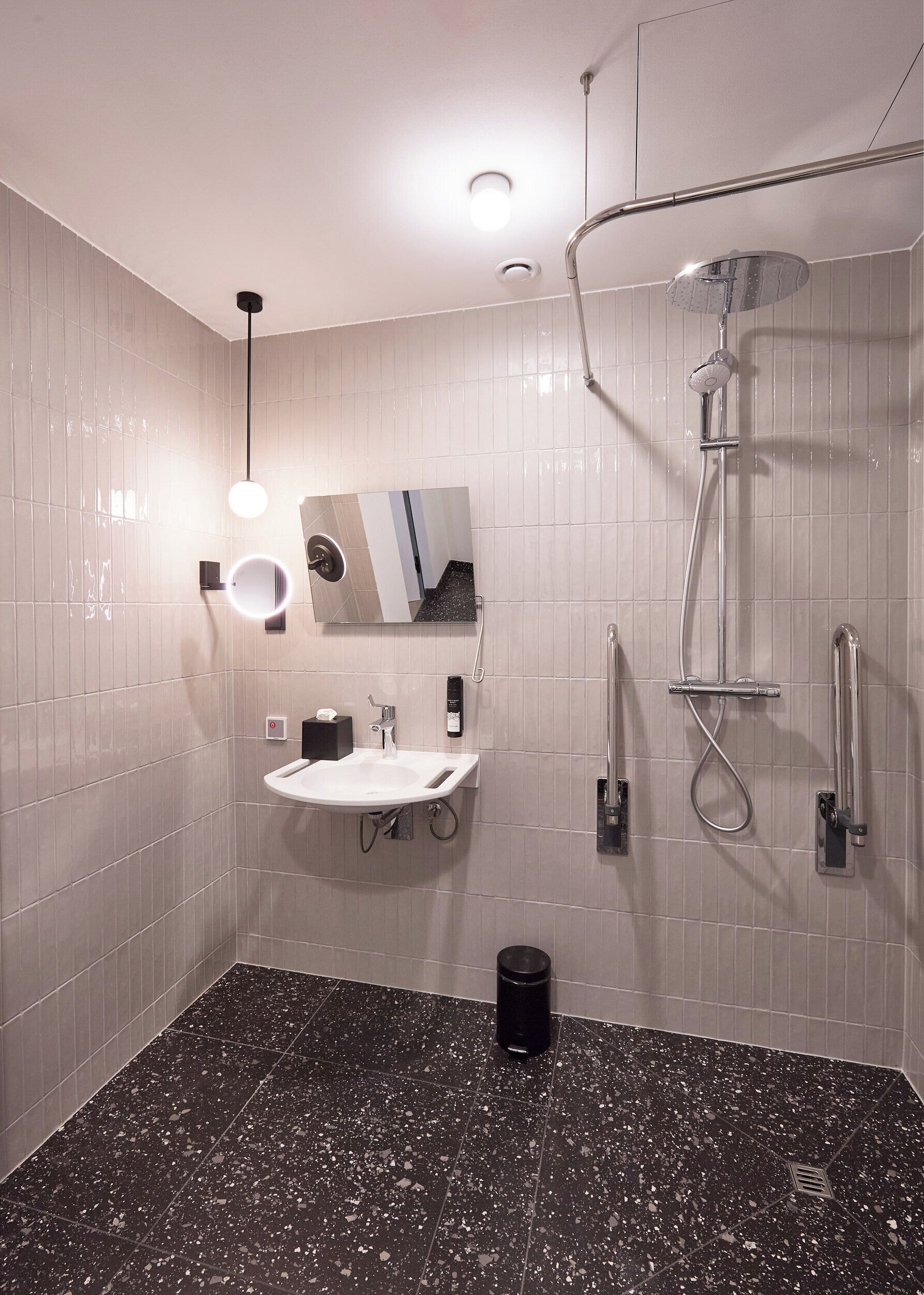 A modern bathroom with a white sink, mirror, and shower.