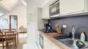 Une cuisine moderne dotée d’un plan de travail en bois, d’un évier en acier inoxydable et d’un four encastré.