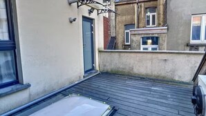 Une terrasse sur le toit dotée d’une lucarne, d’une porte et d’un petit espace extérieur équipé d’un ventilateur.