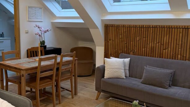 Un appartement moderne de style « loft », comprenant un coin repas, un canapé et une table basse en verre.