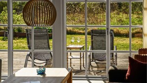 A sunlit patio with a table, chairs, and a hanging light fixture. - Beautiful home in Ejstrupholm with WiFi (Ejstrupholm)