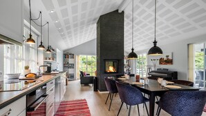 A modern kitchen with a central island, a dining area with a piano, and a fireplace. - Beautiful home in Ejstrupholm with WiFi (Ejstrupholm)