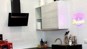 Une cuisine moderne avec des meubles blancs, un réfrigérateur noir, un four à micro-ondes et un néon mural.