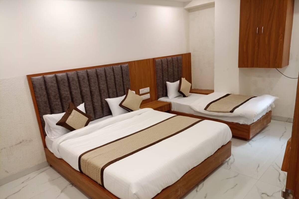 Ein Hotelzimmer mit zwei Einzelbetten, Holzkopfteilen, weißer Bettwäsche und einem Holzschrank.