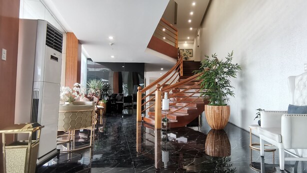 A modern interior with a marble floor, a wooden staircase, and a seating area with a white upholstered chair. - Belvilla Angeles Pampanga Near Clark International Airport Formerly Boss Hotel (Angeles City)