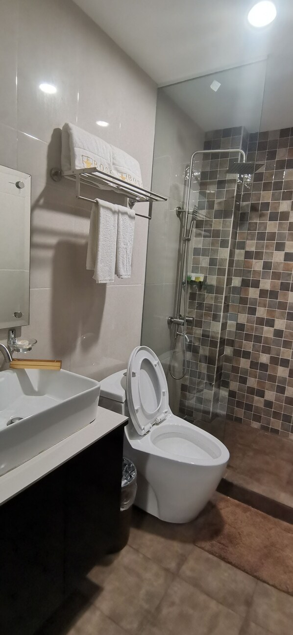 Un baño moderno con lavamanos, inodoro y ducha blancos.