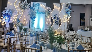A banquet hall with round tables, gold chairs, and a stage with floral decorations and a neon sign. - Belvilla Angeles Pampanga Near Clark International Airport Formerly Boss Hotel (Angeles City)