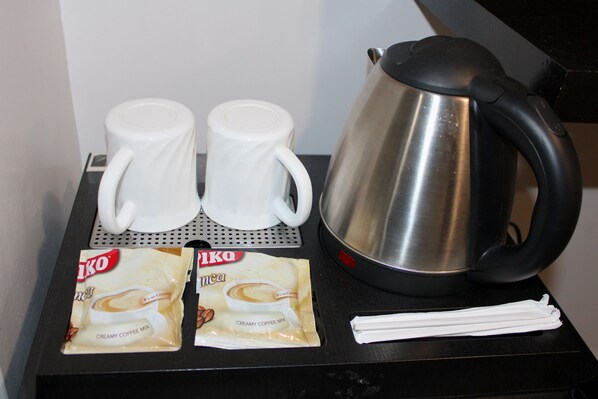 A coffee station with two white cups, a stainless steel coffee pot, and two packets of coffee creamer. - Belvilla Angeles Pampanga Near Clark International Airport Formerly Boss Hotel (Angeles City)