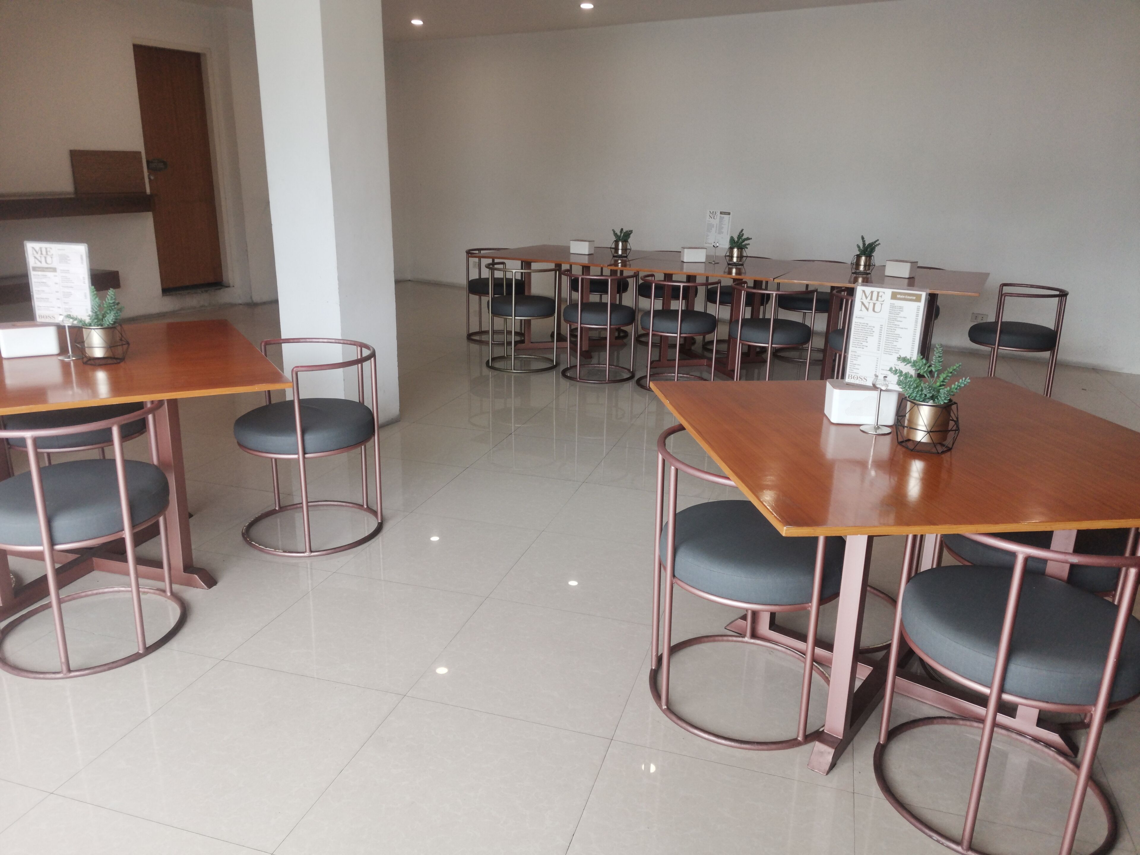 A modern dining area with multiple tables and chairs, featuring a clean, minimalist design with a tiled floor.