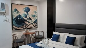 A modern hotel room with a large bed, a small table with two chairs, and a painting on the wall. - Belvilla Angeles Pampanga Near Clark International Airport Formerly Boss Hotel (Angeles City)
