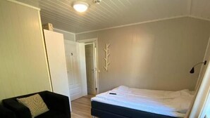 A bedroom with a bed, a sofa, a small table, and a door leading to another room. - Vollanvegen 13 (Mosjøen)