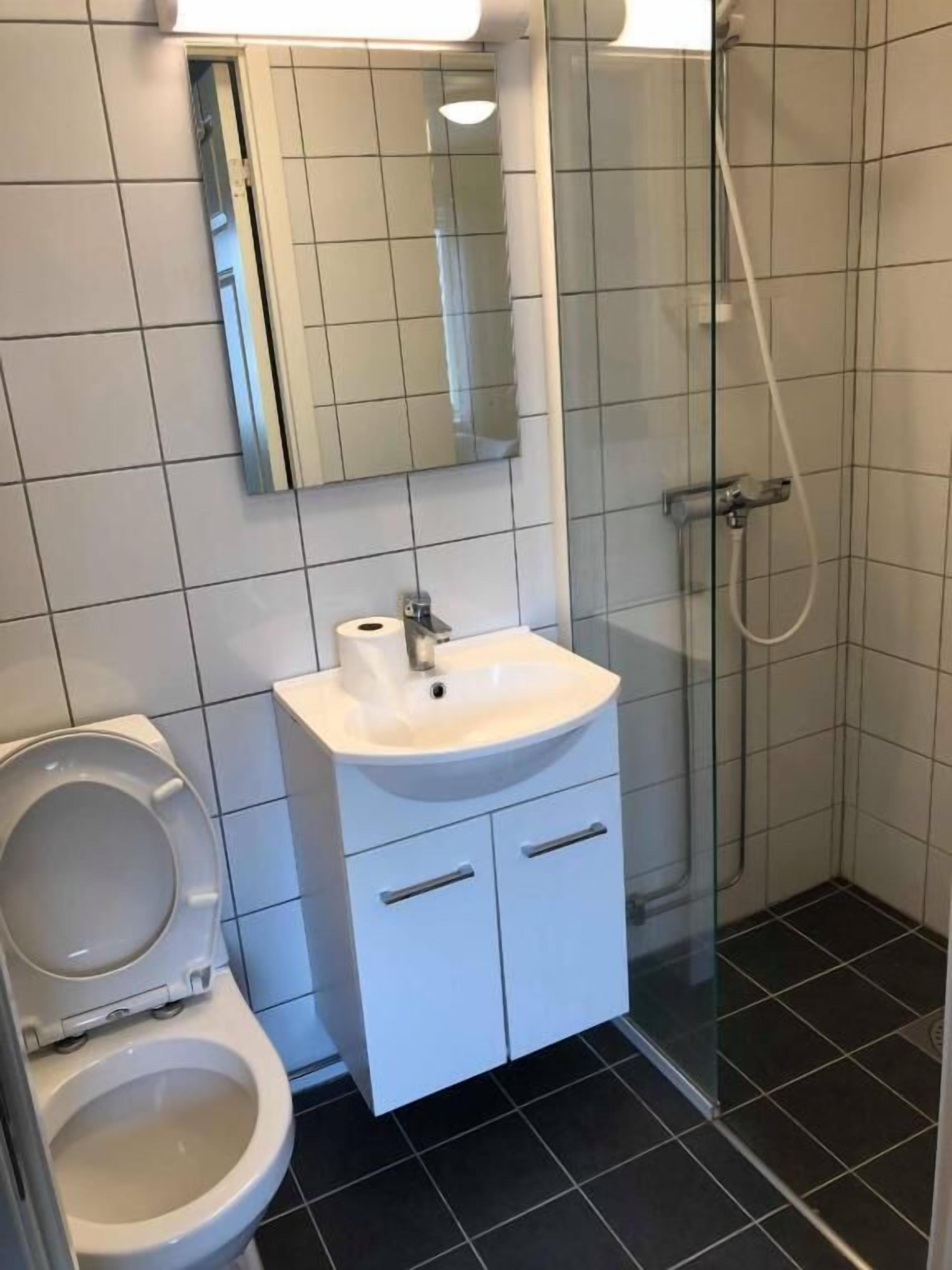 A bathroom with a toilet, sink, and shower.