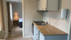 A compact kitchen with a wooden countertop, white cabinets, and a built-in dishwasher. - Vollanvegen 13 (Mosjøen)