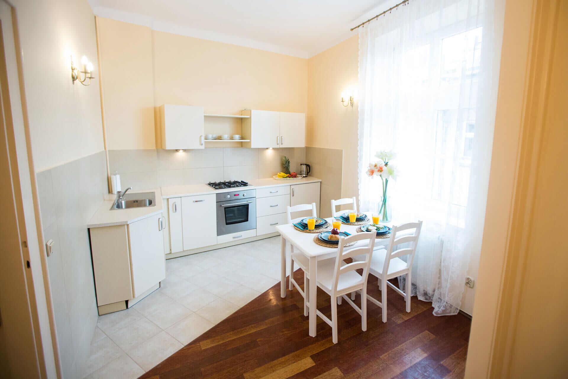 A compact kitchen with white cabinets, a stove, and a dining area with a table set for two.