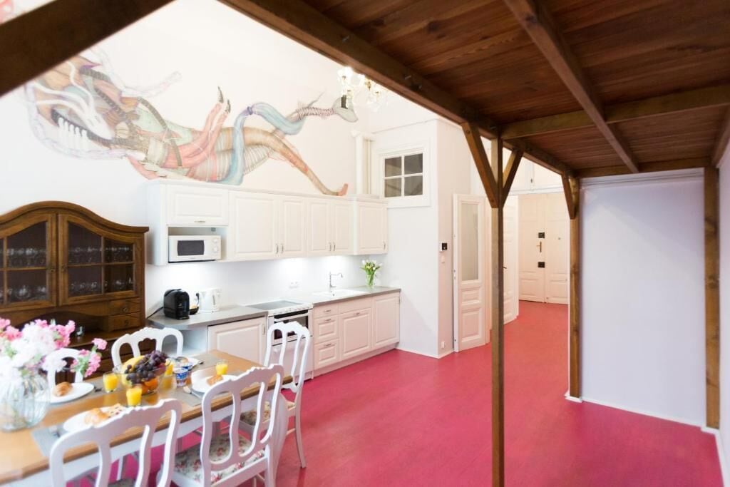 A kitchen with white cabinets, a dining table with chairs, and a red floor.