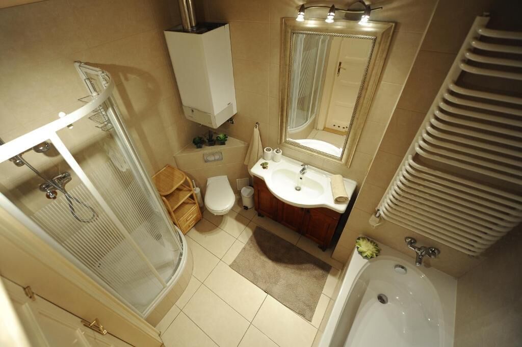Un bagno compatto con box doccia in vetro, un water, un lavandino con specchio e una vasca da bagno.
