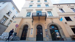 A building with a beige facade, black doors, and a balcony. - Roman Apartments (Kraków)