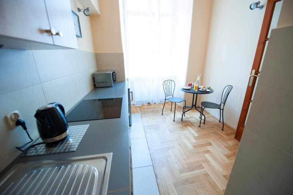 A compact kitchen with a kettle, toaster, and a small dining area with two chairs and a table.