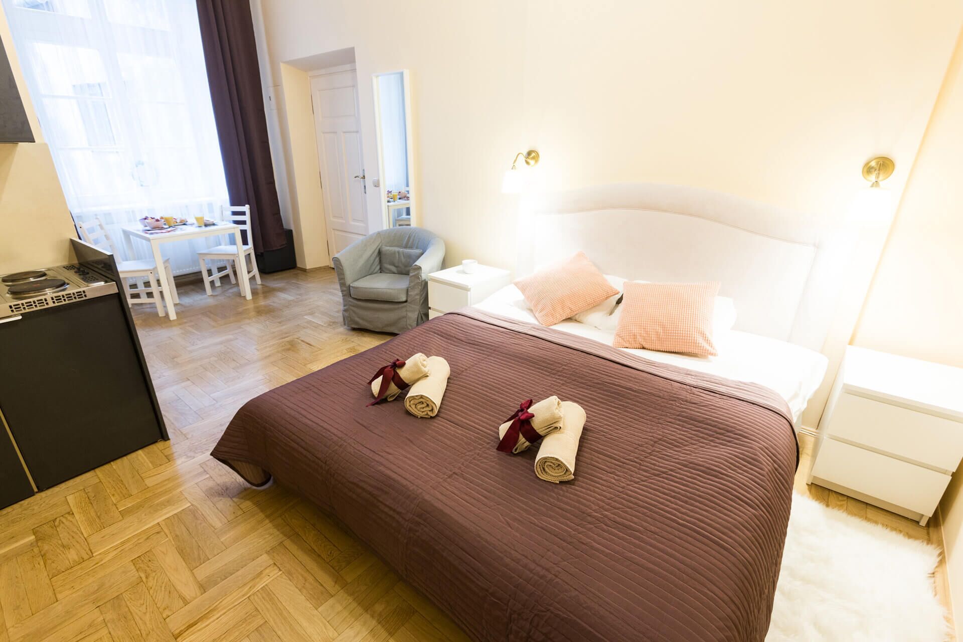 Una habitación de hotel con cama, escritorio, silla y kitchenette.