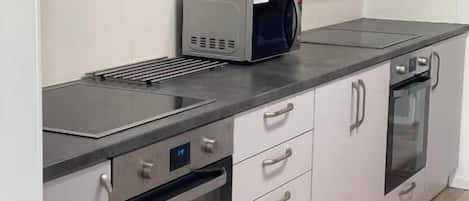 Una cucina moderna con elettrodomestici in acciaio inossidabile, tra cui un forno a microonde, un forno e una cappa aspirante integrata.