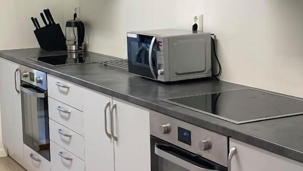 A modern kitchen with stainless steel appliances, including a microwave, oven, and a range hood. - Finnskoggata 20 (Mosjoen)