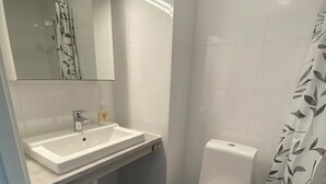 A bathroom with a white sink, mirror, toilet, and shower curtain. - Finnskoggata 20 (Mosjoen)