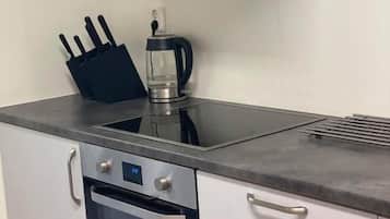 Una cocina con horno de acero inoxidable, cafetera y bloque de cuchillos.