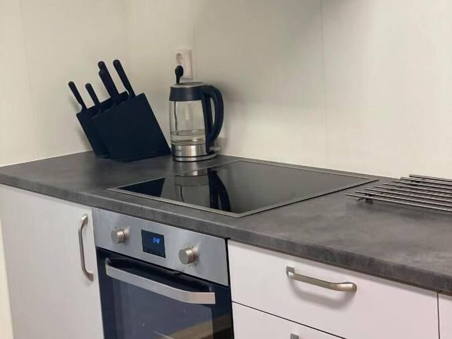 Una cocina con horno de acero inoxidable, cafetera y bloque de cuchillos.
