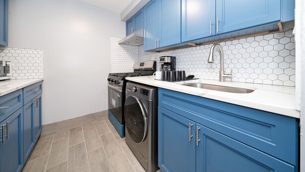 Una cocina moderna con gabinetes azules, una estufa de acero inoxidable, horno empotrado y cafetera.