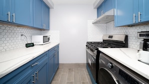 Una cocina moderna con armarios azules, una encimera blanca, un microondas, una estufa y una cafetera.