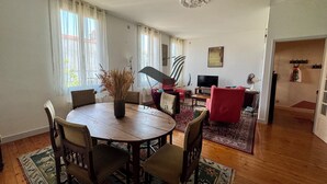Un saló espaiós amb una taula de dinar de fusta, seients còmodes, una televisió i un vas decoratiu.