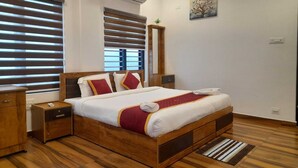 A neatly arranged bedroom with a wooden bed, two bedside tables, a nightstand, and a wall-mounted air conditioner. - VGK RESIDENCY Premium Serviced Apartments (KL)