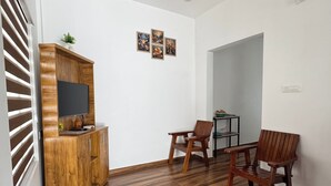 A modern living room with a wooden cabinet, two wooden chairs, a ceiling fan, and a small table. - VGK RESIDENCY Premium Serviced Apartments (KL)