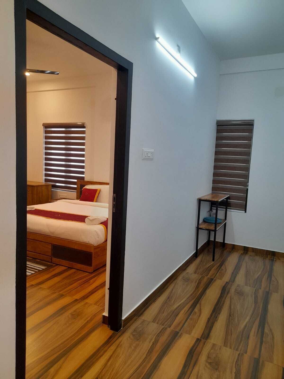 Un dormitorio con cama, una mesita y ventana con persianas.