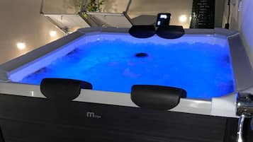 A hot tub with a digital display, surrounded by potted plants and a wooden deck.