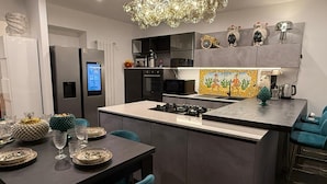 Una cocina moderna con una isla central, electrodomésticos integrados y un salpicadero decorativo.