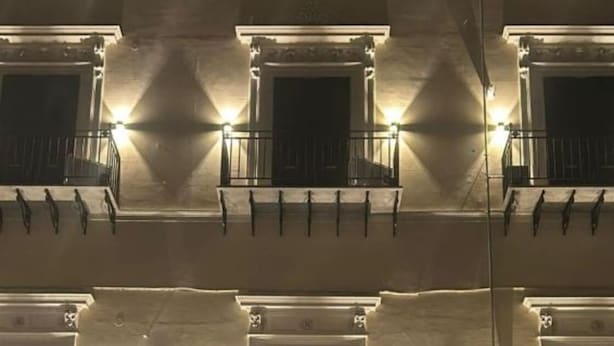 Un edificio de varios pisos con balcones, una entrada central en arco y un cajero automático visible en la planta baja.