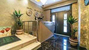 A reception area with a sign reading "RECEPTION," a staircase with a handrail, and two potted plants. - Solo Hotel Taksim (İstanbul)