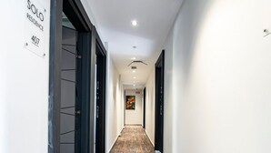 A modern hotel corridor with a carpeted floor, white walls, and doors leading to rooms. - Solo Hotel Taksim (İstanbul)