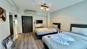 A hotel room with two beds, a TV, a desk, and a door. - Solo Hotel Taksim (İstanbul)