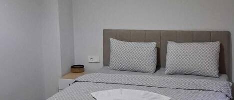 A neatly made bed with a patterned bedspread, a bedside lamp, and a wall-mounted light fixture.
