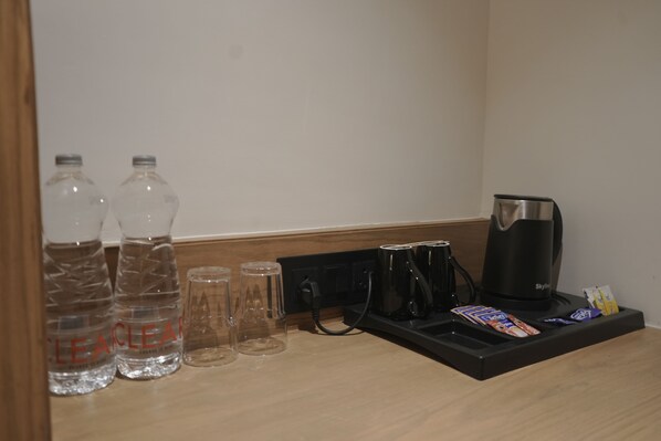 A hotel room's minibar with bottled water, glasses, a coffee maker, and snacks. - Silvotel By Bizzgrow Hotels (Indore)