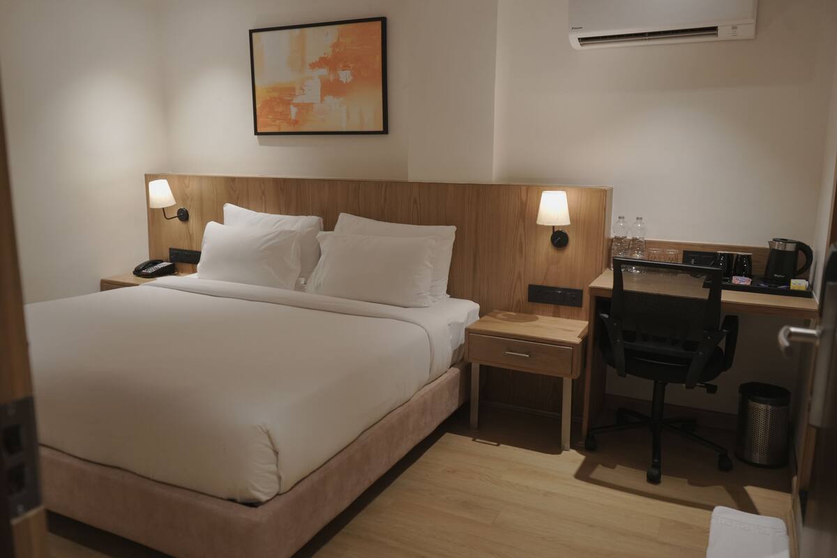 Ein Hotelzimmer mit einem Bett, Nachttischen, einem Schreibtisch mit Stuhl und einer Kaffeemaschine.