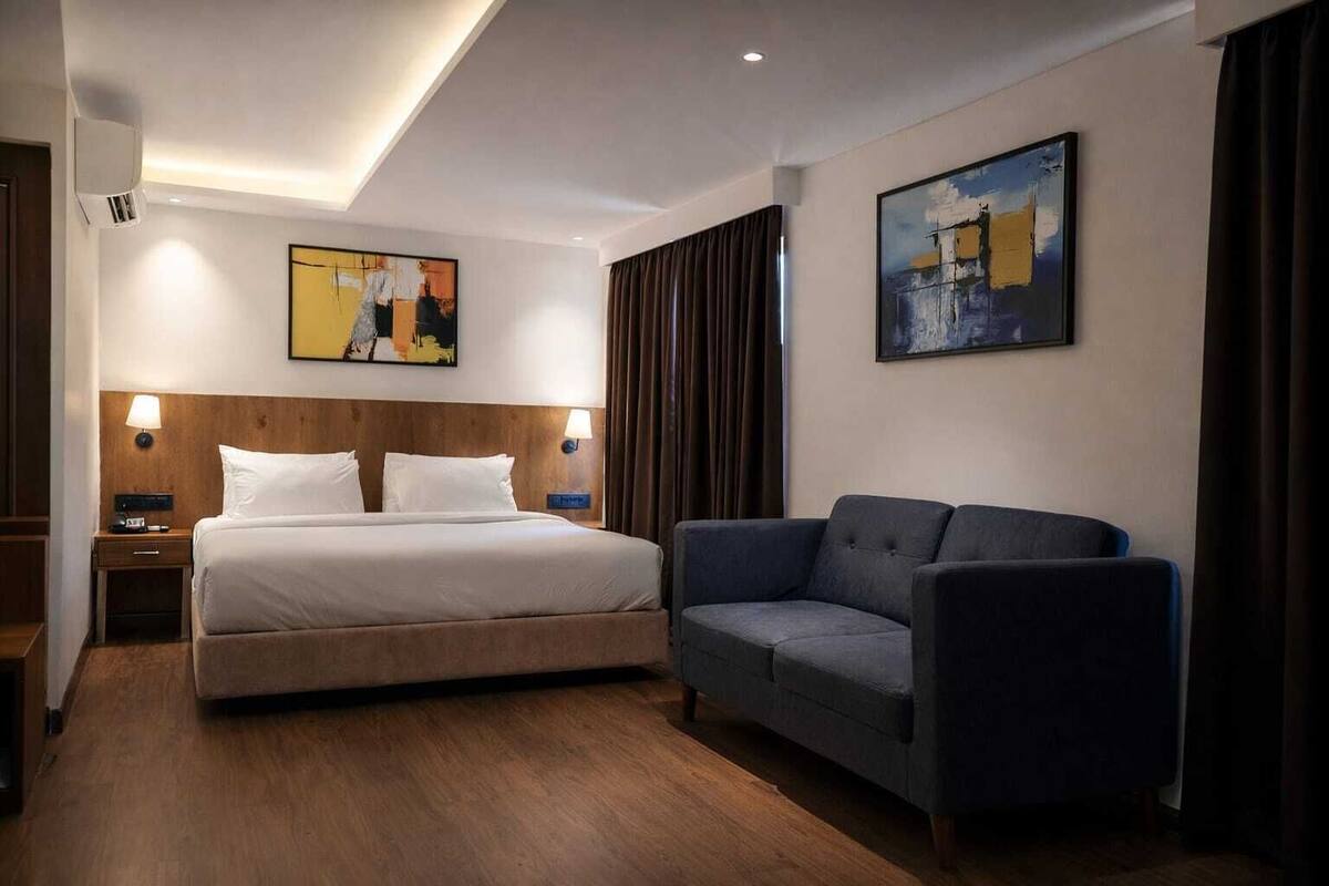 Ein Hotelzimmer mit einem Bett, einer Couch, zwei Wandleuchten und zwei Bildern.