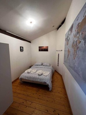 Un dormitorio con una cama, un mapa en la pared y una lámpara en el techo.