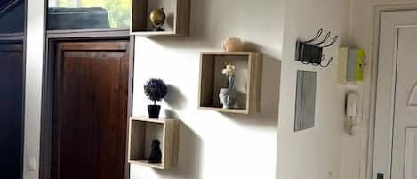 A room with a wooden door, a white radiator, and wall-mounted shelves with decorative items.