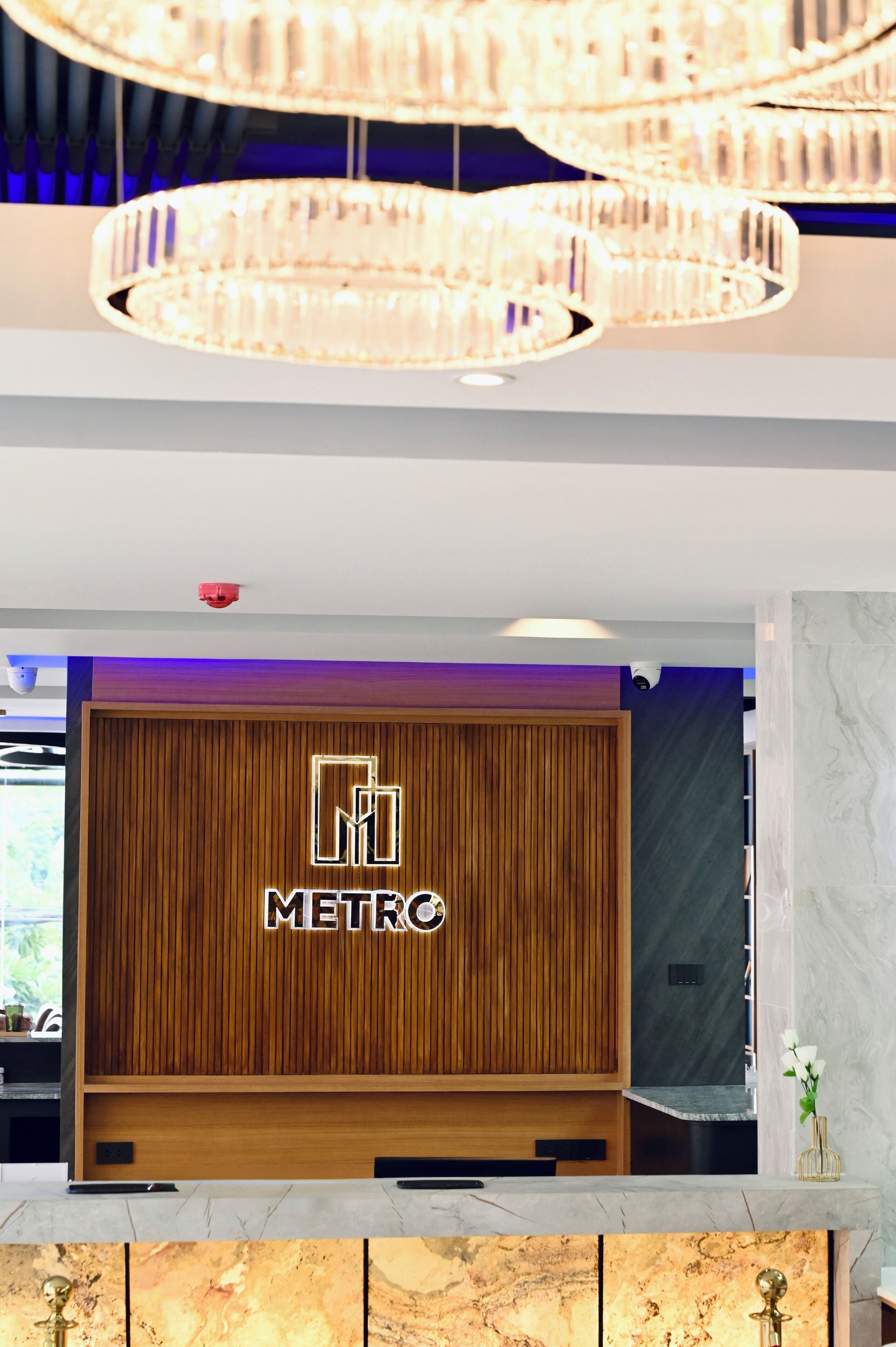 A reception area with a wooden panel wall, a METRO sign, a marble countertop, and a chandelier.