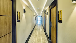 A hotel hallway with numbered doors, a marble floor, and recessed lighting. - Metro Hotel Phahonyothin 35 (Bangkok)