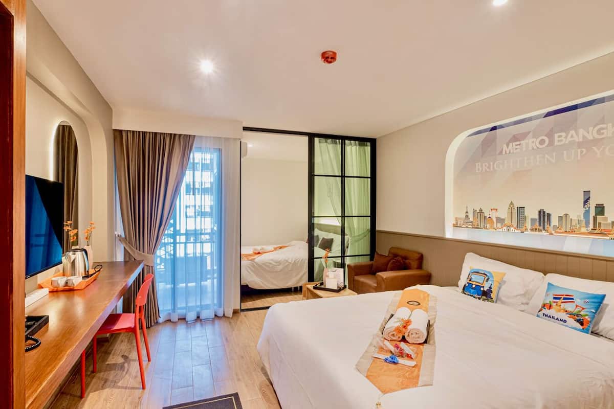 Une chambre d’hôtel équipée d’un lit, d’un bureau, d’une chaise, d’une télévision et d’une fresque murale représentant un paysage urbain.