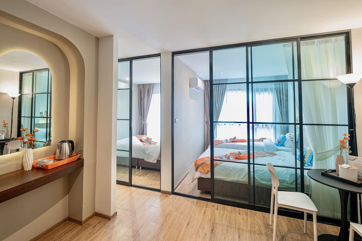 Une chambre d’hôtel dotée d’une grande porte-fenêtre coulissante donnant sur un balcon, d’un plancher en bois, d’un bureau avec un plateau contenant divers objets et d’un lit offrant une vue agréable.